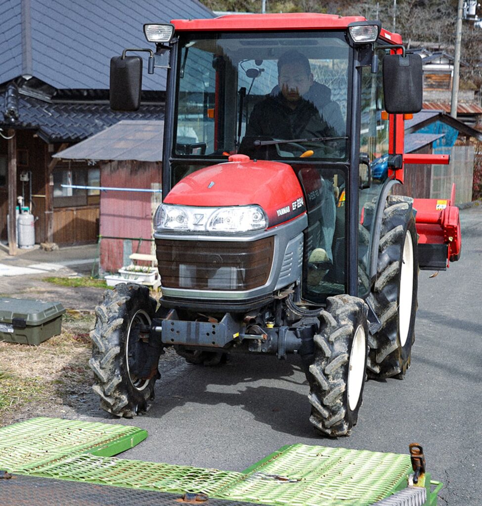 農機具を大型トラックに乗せようとしている男性