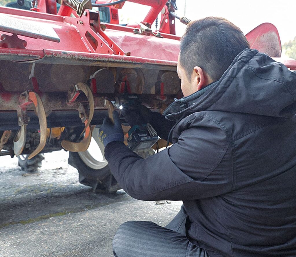 農機具のチェックをしている男性の後ろ姿